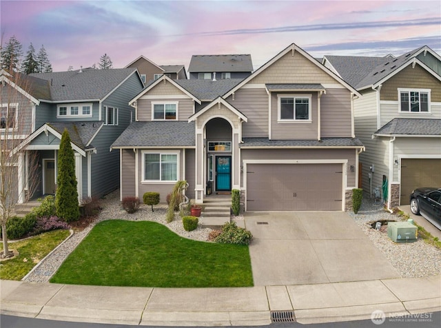 view of front facade featuring a garage, a lawn, concrete driveway, and roof with shingles