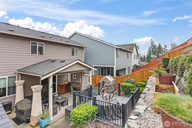 back of property featuring roof with shingles, a deck, and fence