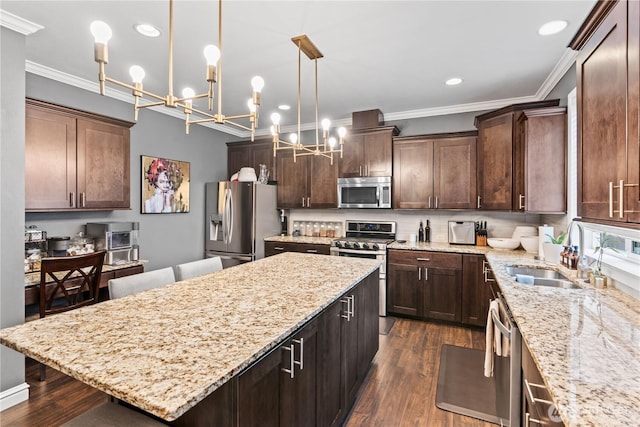 kitchen featuring a kitchen island, a sink, stainless steel appliances, dark wood-type flooring, and crown molding