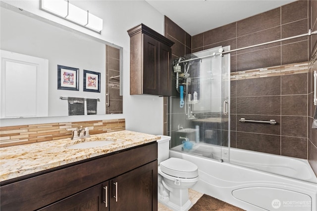 bathroom featuring decorative backsplash, toilet, vanity, and shower / bath combination with glass door