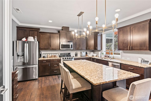 kitchen with dark wood-type flooring, a sink, stainless steel appliances, dark brown cabinetry, and decorative backsplash