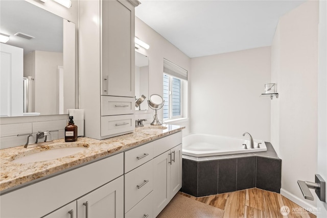 full bathroom featuring a sink, visible vents, a garden tub, and wood finished floors