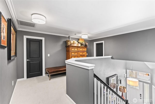 hall with visible vents, baseboards, carpet, ornamental molding, and an upstairs landing