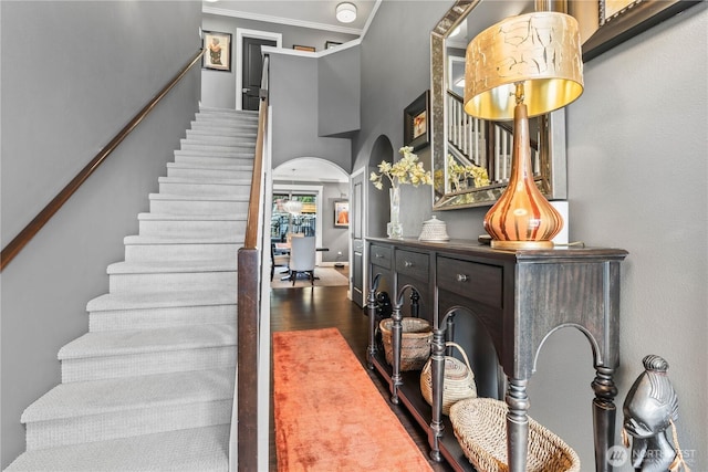 stairs with crown molding, baseboards, a high ceiling, wood finished floors, and arched walkways