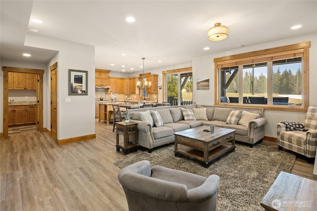 living area with baseboards, light wood-type flooring, and recessed lighting