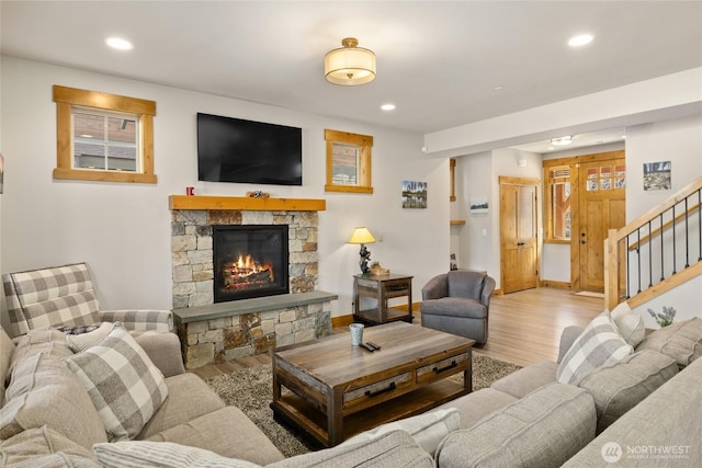 living room with stairs, recessed lighting, a fireplace, and wood finished floors