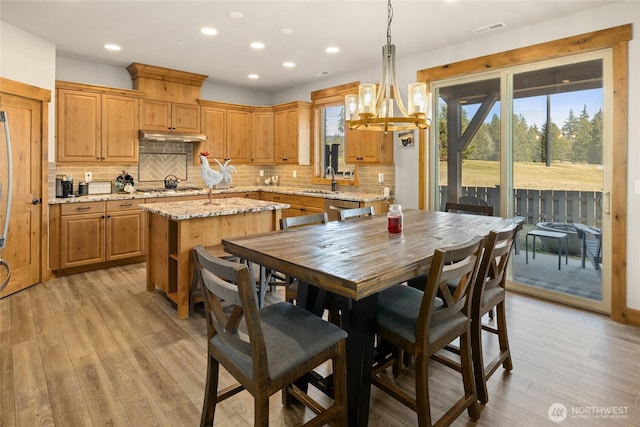 kitchen with light wood-style floors, a kitchen island, appliances with stainless steel finishes, and backsplash