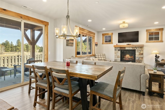 dining room featuring a fireplace, wood finished floors, visible vents, and recessed lighting