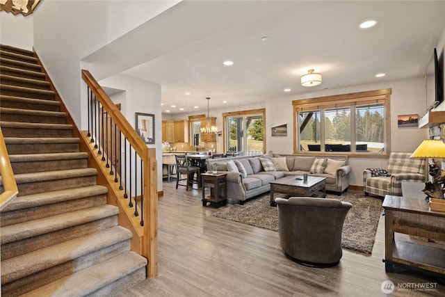 living area featuring light wood-style floors, recessed lighting, a chandelier, and stairs