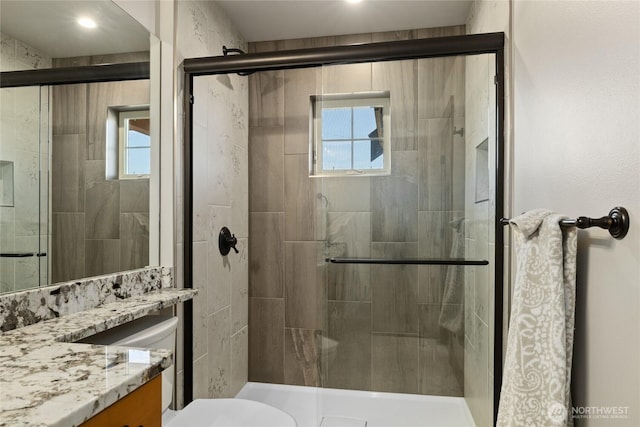 full bathroom featuring toilet, a stall shower, and vanity