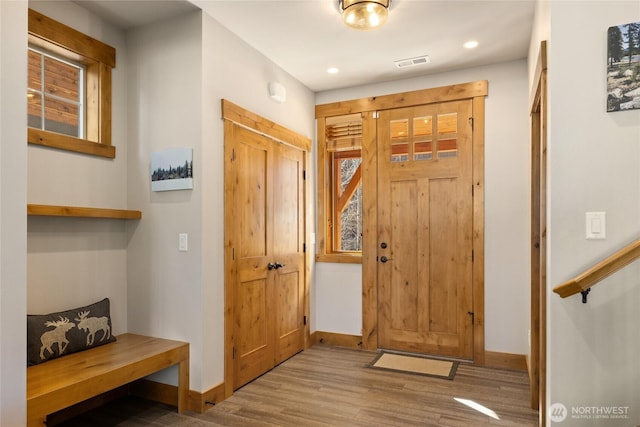 entrance foyer with recessed lighting, visible vents, stairway, wood finished floors, and baseboards