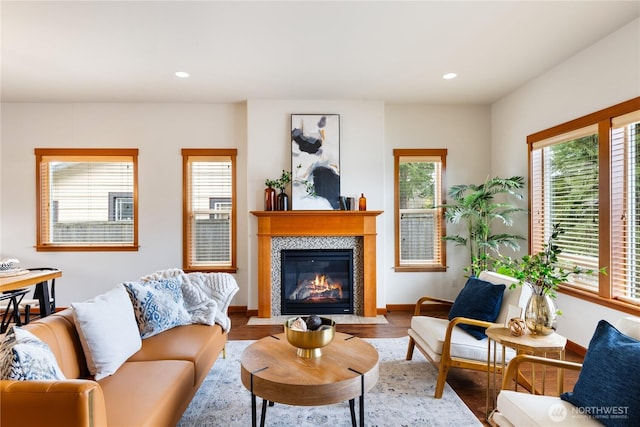 living room featuring recessed lighting, baseboards, a fireplace with flush hearth, and wood finished floors