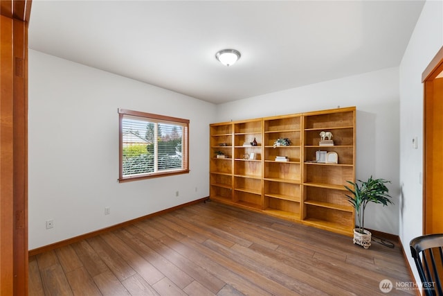 unfurnished room featuring baseboards and wood-type flooring