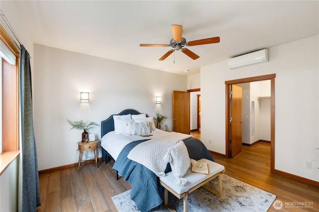 bedroom featuring a wall mounted air conditioner, baseboards, ceiling fan, and light wood finished floors