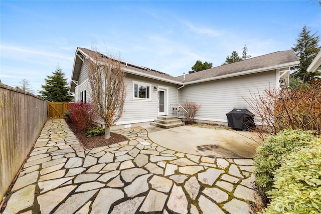 back of property with solar panels, a patio, fence private yard, and crawl space