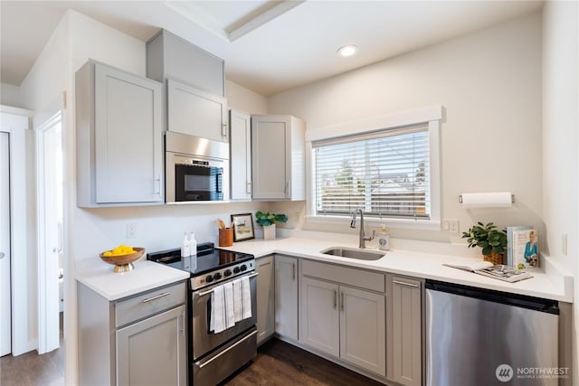 kitchen with light countertops, gray cabinetry, appliances with stainless steel finishes, and a sink