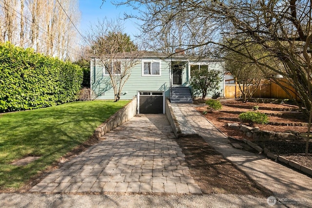 view of front facade featuring an attached garage, decorative driveway, a front yard, and fence