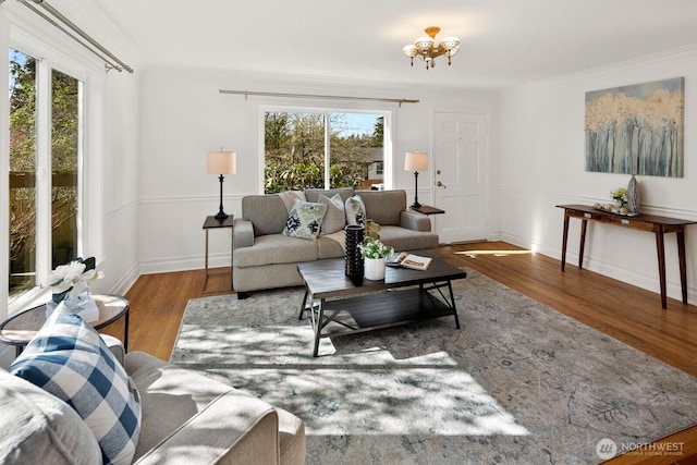 living area with a wealth of natural light, wood finished floors, and ornamental molding