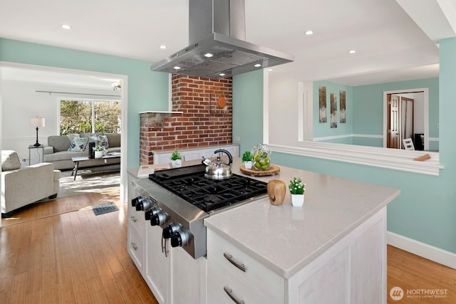 kitchen with stainless steel gas cooktop, light countertops, island exhaust hood, light wood-style floors, and white cabinetry