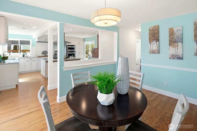 dining space with light wood-style floors and baseboards