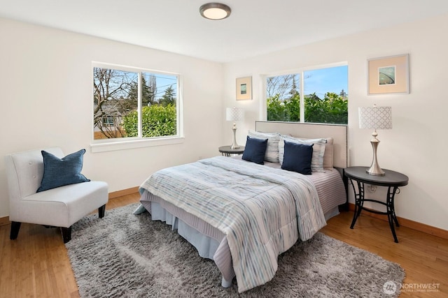 bedroom with multiple windows, wood finished floors, and baseboards