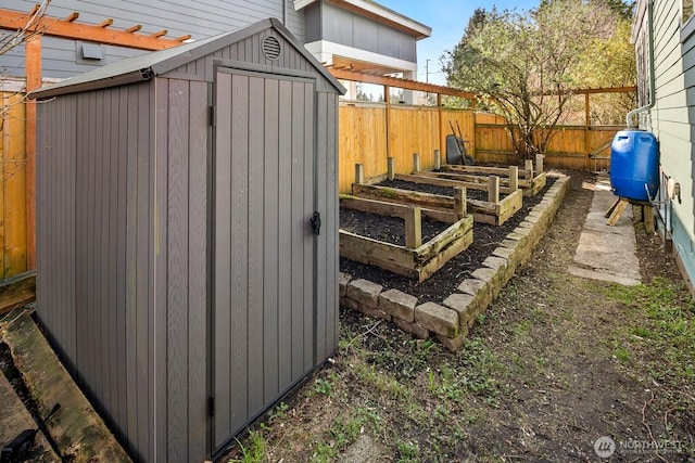 view of yard with an outdoor structure, a garden, a fenced backyard, and a shed