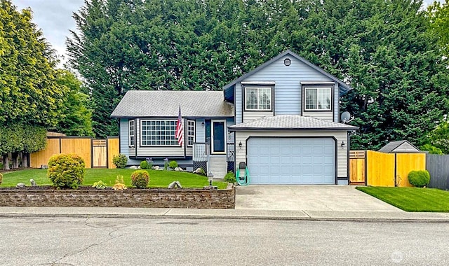 tri-level home featuring driveway, an attached garage, a front lawn, and fence