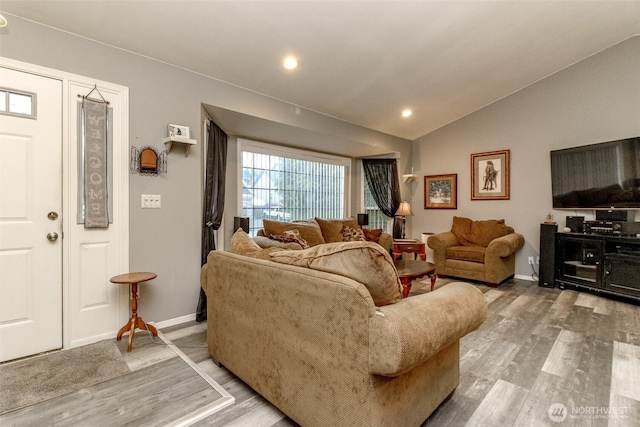 living area featuring vaulted ceiling, light wood-style floors, and baseboards