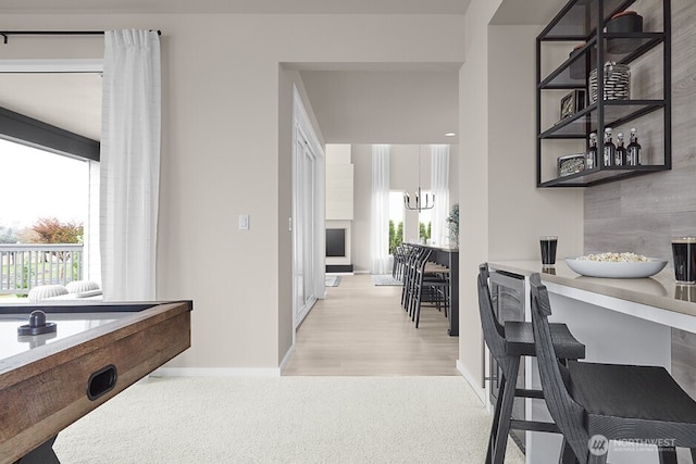 interior space with a bar, light carpet, baseboards, and a chandelier