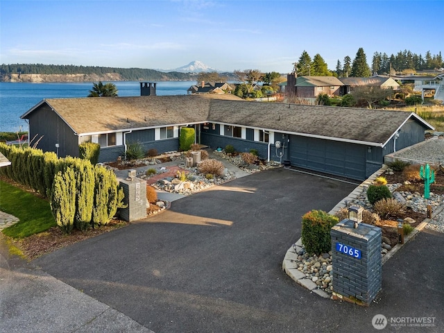 ranch-style home featuring a water and mountain view, a garage, and driveway