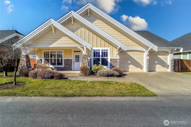 craftsman house featuring driveway, stone siding, fence, board and batten siding, and an attached garage