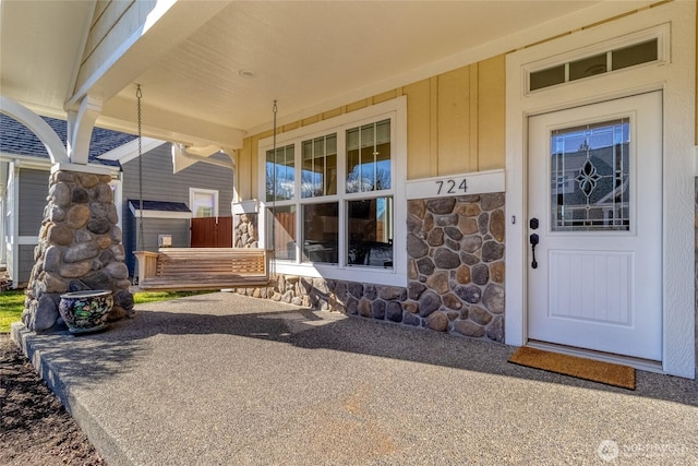 property entrance featuring stone siding and covered porch