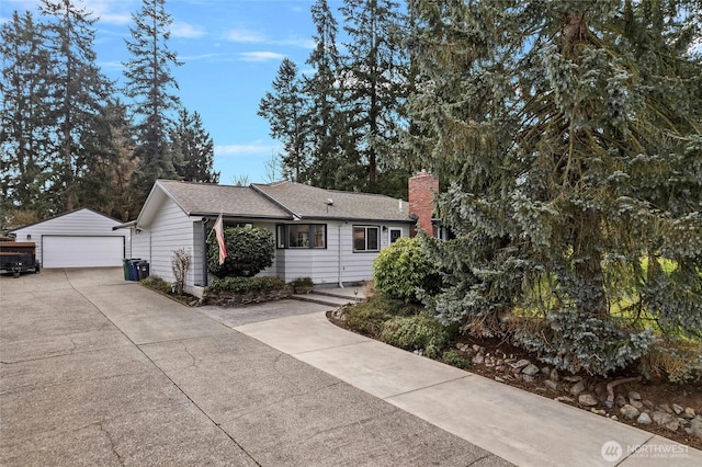 ranch-style house featuring a shingled roof, an outdoor structure, a detached garage, and a chimney