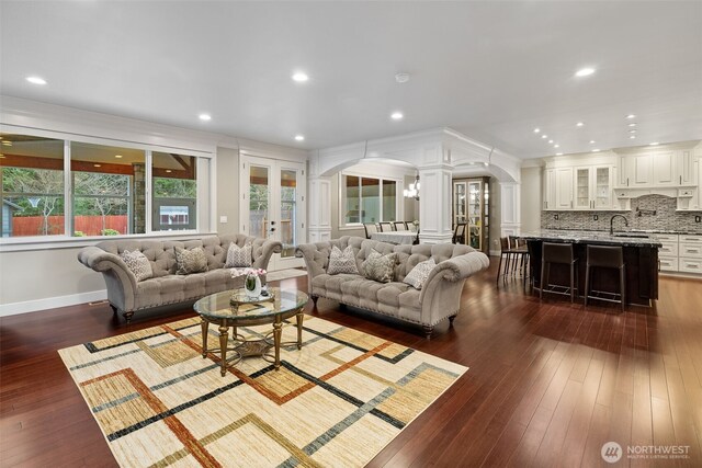 living area with arched walkways, recessed lighting, dark wood-type flooring, and ornate columns