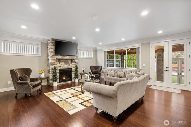 living area featuring french doors, dark wood-style floors, a fireplace, and ornamental molding