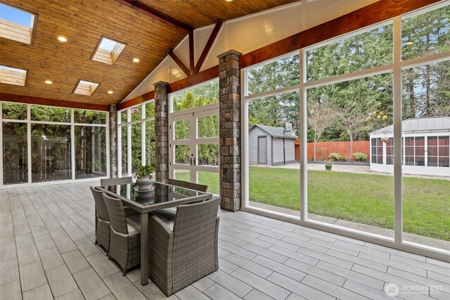 unfurnished sunroom with lofted ceiling with skylight and wood ceiling