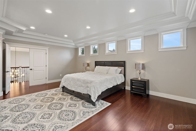 bedroom featuring a raised ceiling, wood finished floors, and crown molding