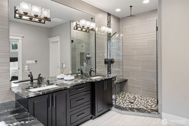 ensuite bathroom featuring a sink, connected bathroom, double vanity, and a shower stall