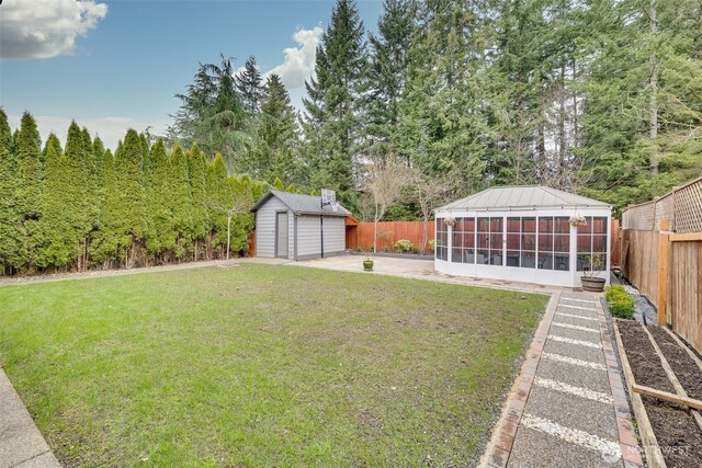 view of yard featuring an outdoor structure, a fenced backyard, and a sunroom