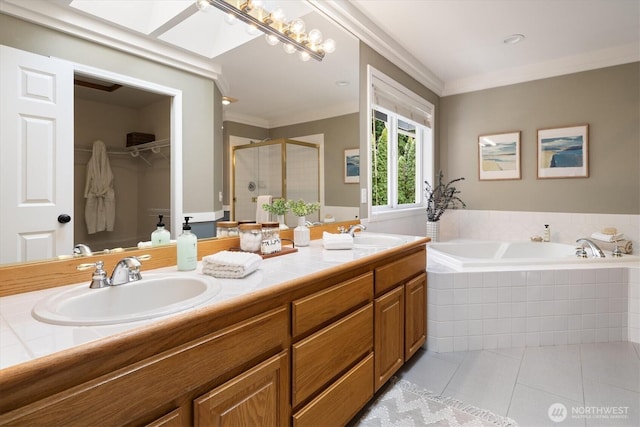 full bathroom with a skylight, a sink, tile patterned flooring, a shower stall, and a garden tub