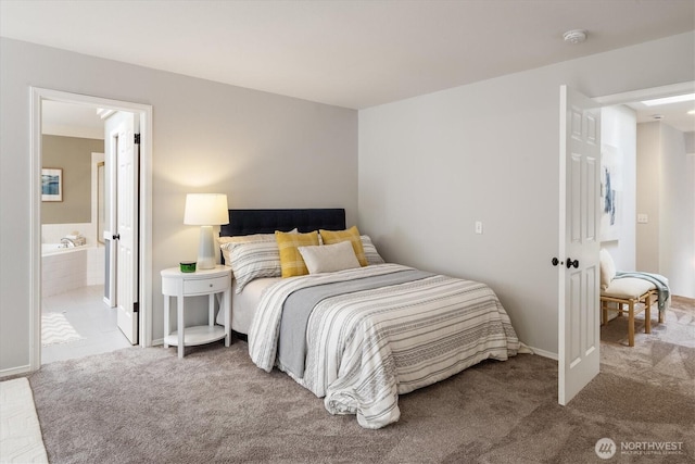 carpeted bedroom with ensuite bath and baseboards