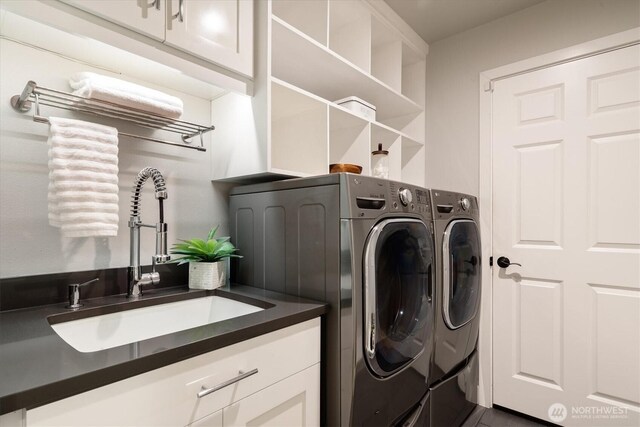 washroom featuring a sink, cabinet space, and independent washer and dryer