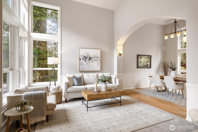 living room featuring wood finished floors, a high ceiling, a decorative wall, and a healthy amount of sunlight