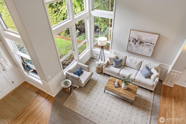 living area with a decorative wall, a wainscoted wall, and wood finished floors