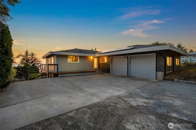 view of front of home with concrete driveway, an attached garage, and roof mounted solar panels