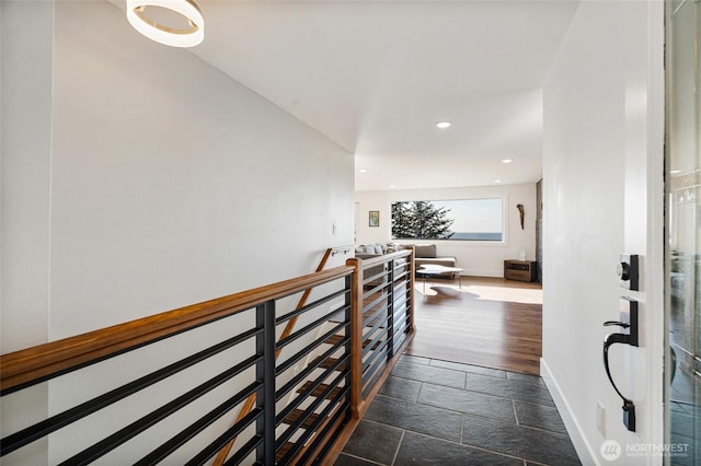 corridor featuring stone tile floors, an upstairs landing, recessed lighting, and baseboards