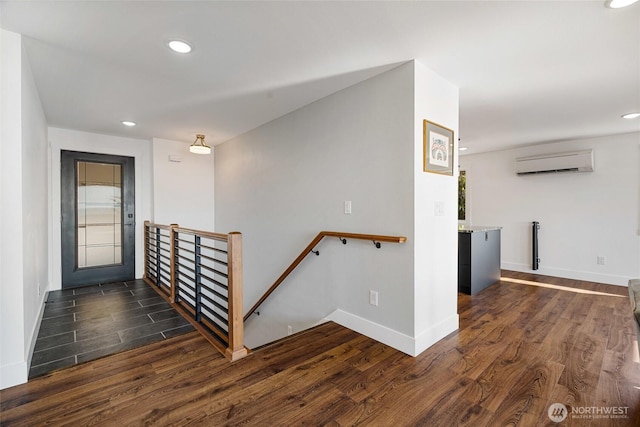 hallway featuring dark wood-type flooring, an upstairs landing, baseboards, and a wall mounted AC