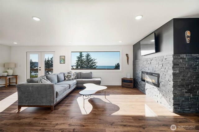 living area featuring a stone fireplace, recessed lighting, french doors, and wood finished floors