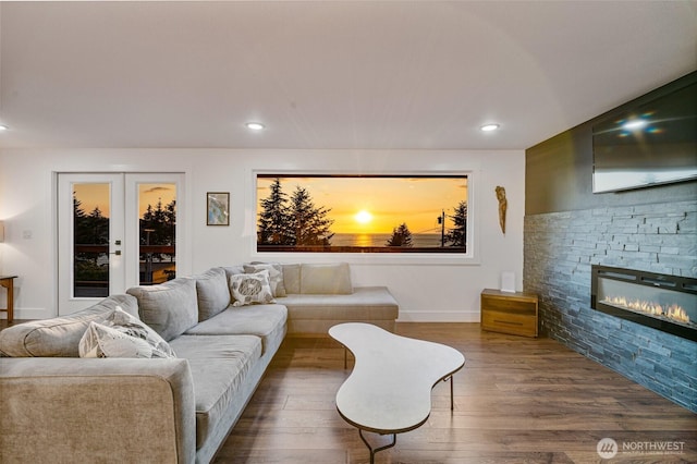 living room featuring recessed lighting, french doors, a stone fireplace, and dark wood finished floors