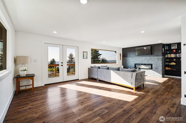 unfurnished living room featuring wood finished floors, baseboards, recessed lighting, a fireplace, and french doors